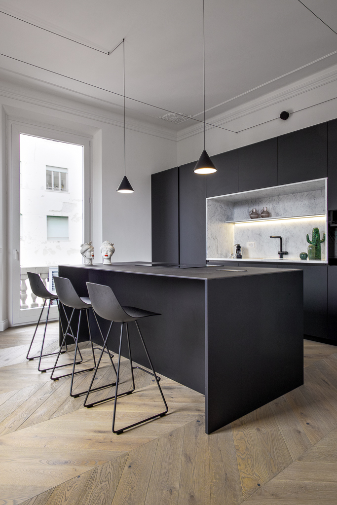 Modern matte black lacquered kitchen interior with island unit and stools in the foreground, full cabinetry visible in the background. Contemporary luxury home design.                       PROGETTO ARCH. CATERINA PEGAZZANO                                     GETTY IMAGES 2282949427           ALAMY RM 3E95FAR 4/2026