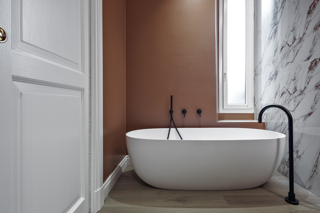 Modern bathroom interior with a freestanding bathtub and wooden flooring in the foreground                 Project architeto Laura Pegazzano