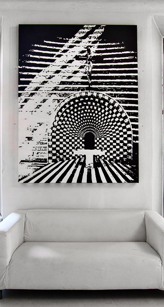 Interni dello studio di Fabrizio Musa a Como, in primo piano, alla parete sopra il divano bianco, un'opera in bianco e nero